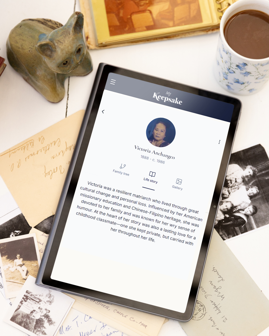A tablet showing a Keepsake ancestor life story, surrounded by old photographs and letters